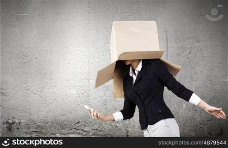 Anonymous call. Businesswoman using mobile phone wearing carton box on head
