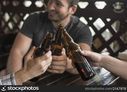 anonymous friends clinking bottles bar table