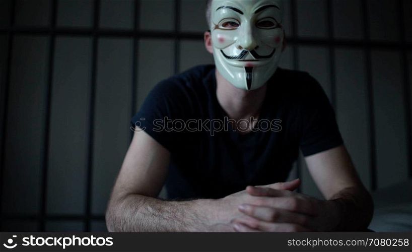 Anonymous hacker in prison glares at camera