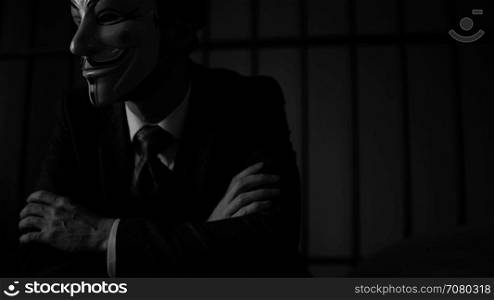 Anonymous hacker looks off camera in prison (B/W Version)