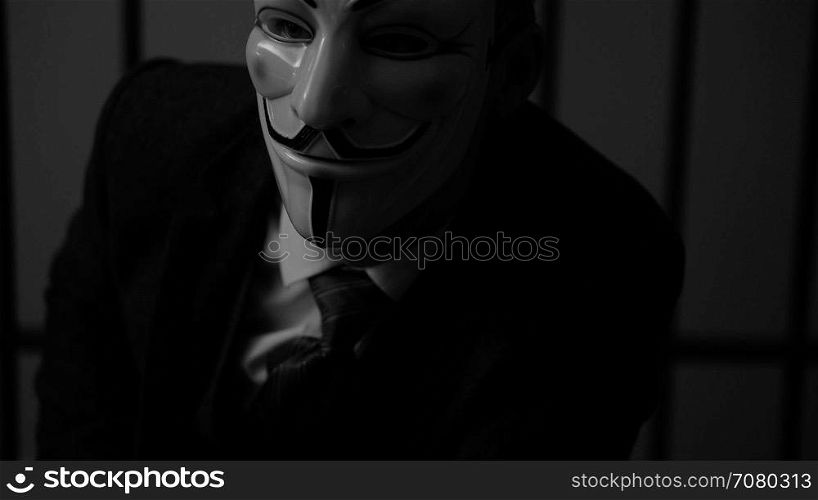 Anonymous hacker man stares into camera in prison (B/W Version)