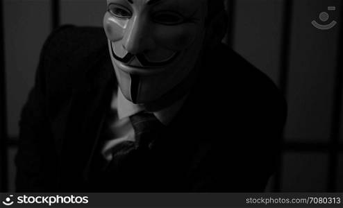 Anonymous hacker man stares into camera in prison (B/W Version)