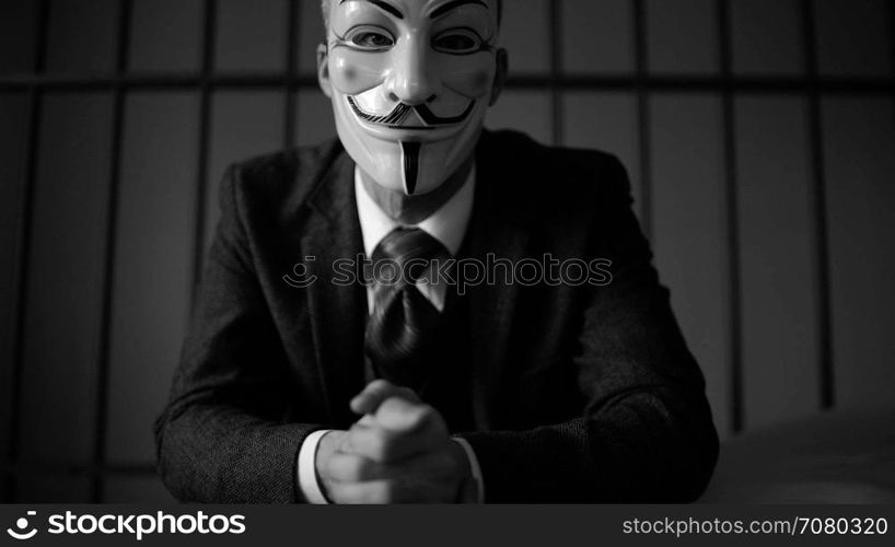 Anonymous hacker seated in prison (B/W Version)