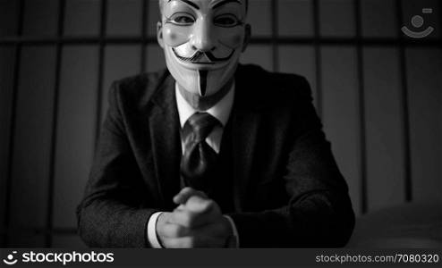 Anonymous hacker seated in prison (B/W Version)