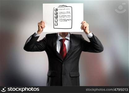Anonymous interview. Businessman hiding his face behind paper sheet with sketches