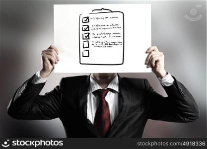Anonymous interview. Businessman hiding his face behind paper sheet with sketches