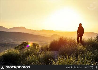 Anonymous silhouette of a man at mountain top against a foggy landscape. First man in another world. Concept of another planet discovering a new land. Copy space. Anonymous silhouette of a man at mountain top against a foggy landscape. First man in another world. Concept of another planet discovering a new land. Copy space.