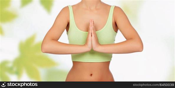 Anonymous woman doing yoga with green leaves of background