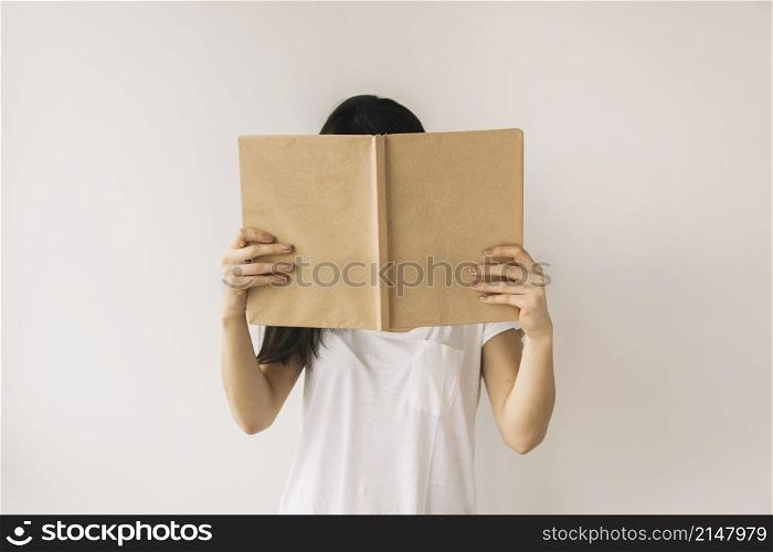 anonymous woman reading near white wall
