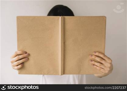 anonymous woman showing book cover camera