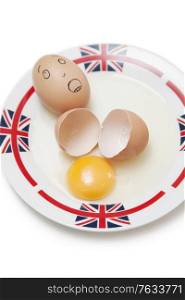 Anthropomorphic brown egg with egg shells and yoke in plate