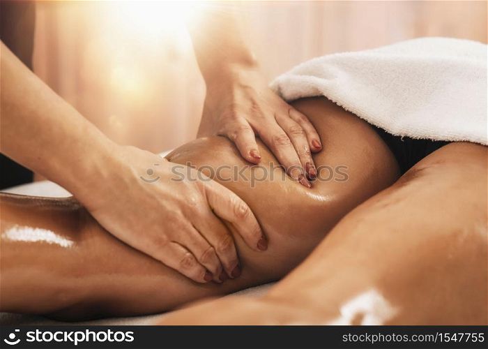 Anti cellulite massage of a female thigh. Hands applying pressure on hamstrings and improving circulation