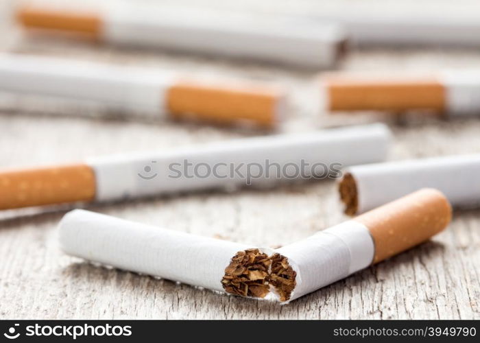 Anti-smoking background with broken cigarette on wooden surface