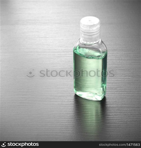 Antibacterial alcohol-containing hand sanitizer in a plastic bottle. Hand sanitizer in green color on a wood table. Antibacterial hand gel.