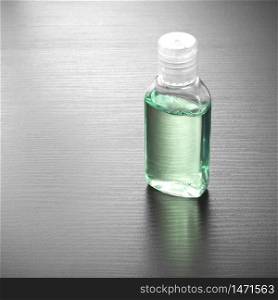 Antibacterial alcohol-containing hand sanitizer in a plastic bottle. Hand sanitizer in green color on a wood table. Antibacterial hand gel.