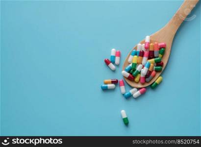 Antibiotic capsule pills on spoon and blue background. Antibiotic drug resistance. Pharmaceutics. Medical health care. Prescription drugs. Drug use problems. Dose of medicine. Pharmaceutical care.