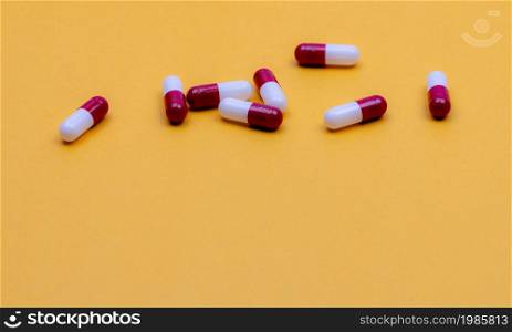 Antibiotic capsule pills on yellow background. Pharmaceutical industry. Prescription drug. Red-white capsule pills. Pharmaceutical product. Pharmacy web banner. Health insurance and health budget.