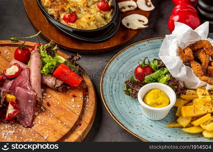 antipasti, chicken fillet and casserole mushrooms on stone table