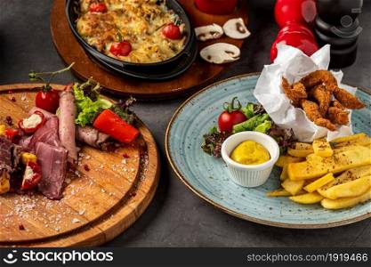 antipasti, chicken fillet and casserole mushrooms on stone table