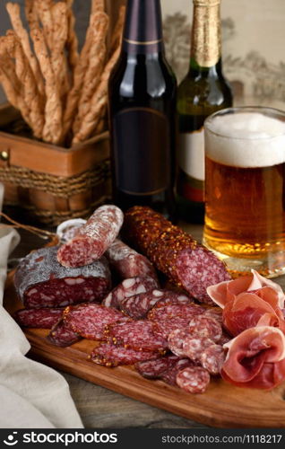 Antipasti dish with bacon, jerky, salami, crispy grissini with cheese. A meat appetizer is a great idea for a beer.