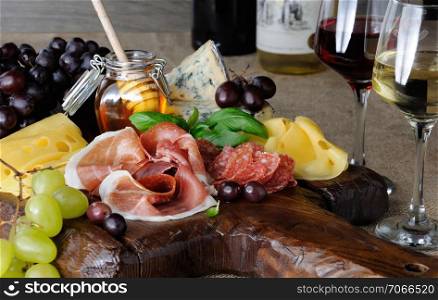 Antipasto catering platter with jerky bacon, prosciutto, salami, cheese and grapes on a wooden background