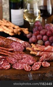 Antipasto. Dish with sausage, dried ham, salami, crispy grissini with grapes. A meat appetizer is a great idea for wine.