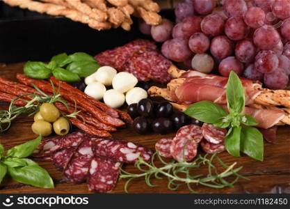 Antipasto. Dish with sausage, dried ham, salami, crispy grissini with grapes. A meat appetizer is a great idea