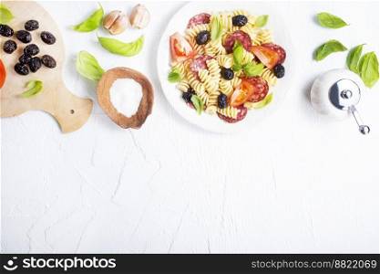 Antipasto salad with pasta, tomato, olives, red onion, bell pepper, salami