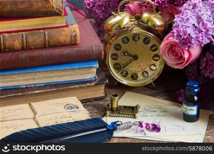 antique alarm clock, pile of mail with blue quill pen and flowers