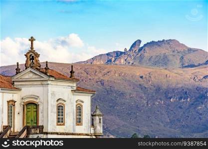 Antique baroque church in the city of Ouro Preto in Minas Gerais with the mountains and peak of Itacolomi in the background during sunset. Antique baroque church in the city of Ouro Preto