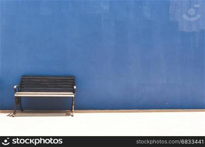Antique bench on blue concrete background.
