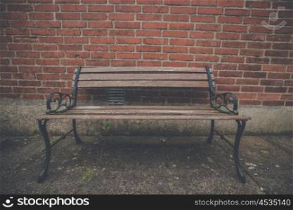 Antique bench up against a red brick wall
