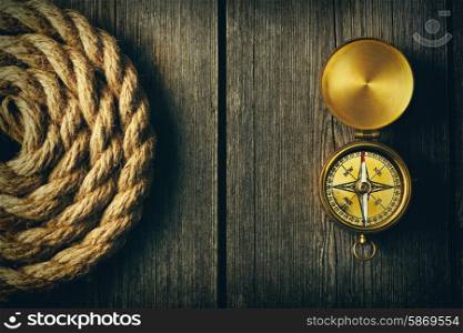 Antique brass compass and rope over wooden background