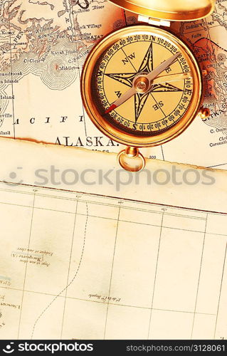 Antique brass compass over old Alaska map