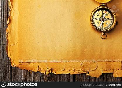 Antique brass compass over old paper background