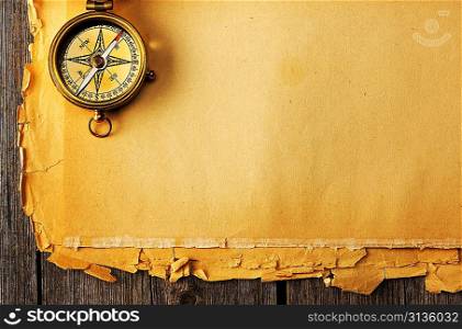 Antique brass compass over old paper background