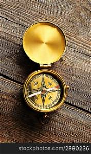 Antique brass compass over wooden background