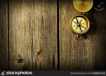 Antique brass compass over wooden background
