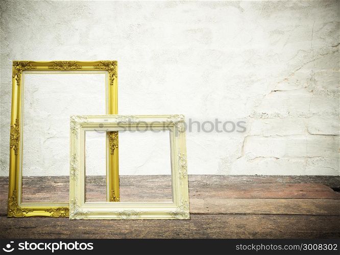Antique classical frame on wooden table with concrete texture on background.