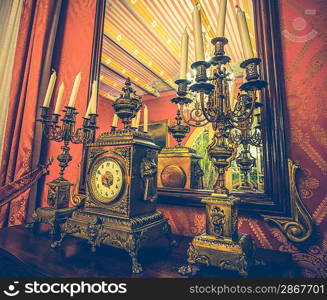 Antique clock and chandelier against mirror