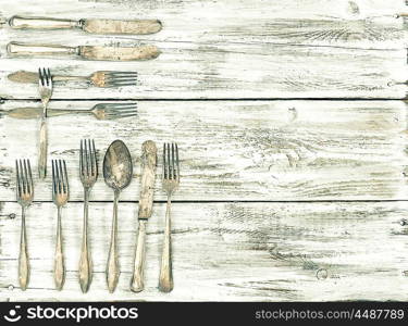 Antique cutlery on rustic wooden background. Retro kitchen utensils. Vintage style toned picture