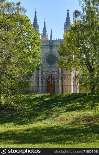 Antique gothic chapel lit by the rays of the sun against. Antique gothic chapel in the park on a background of trees and sky