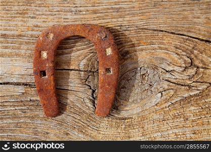 Antique horseshoe luck symbol rusted on vintage wood background