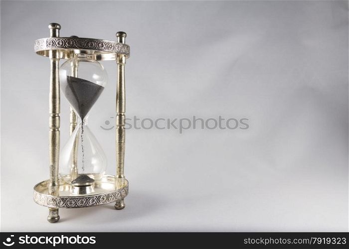 Antique hourglass, black sand, textured background. Left of image, blank space on right , landscape, top half almost full.