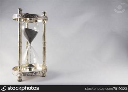 Antique hourglass, black sand, textured background. Left of image, blank space on right , landscape, top half almost full.