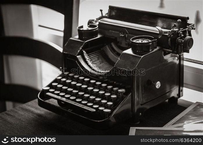 antique manual typewriter on the table of the writer, in front of the window