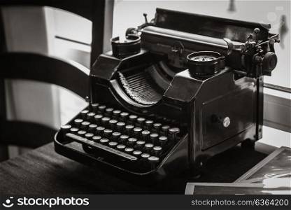 antique manual typewriter on the table of the writer, in front of the window