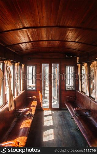 Antique old classic train wooden interior with curtain and afternoon light. Beautiful wood bench seat, hard wood ceiling and floor.
