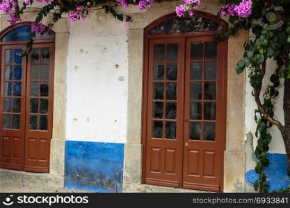 Antique Portuguese Architecture: Old Brown Door near Vegetation in Obidos Main Street - Portugal. Antique Portuguese Architecture: Old Brown Door near Vegetation