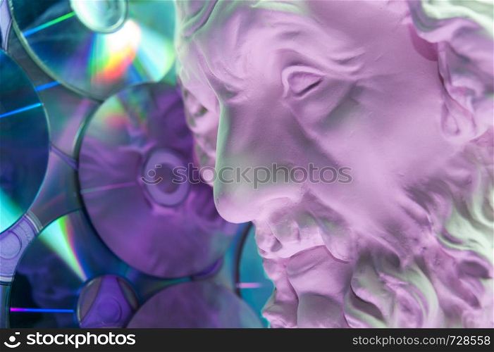 Antique statue of Homer head closeup against the background of glitter CDs. Concept of music, style, vintage. Toned.. Antique statue of Homer head close up on a glitter CDs background. Concept of music, style, vintage.